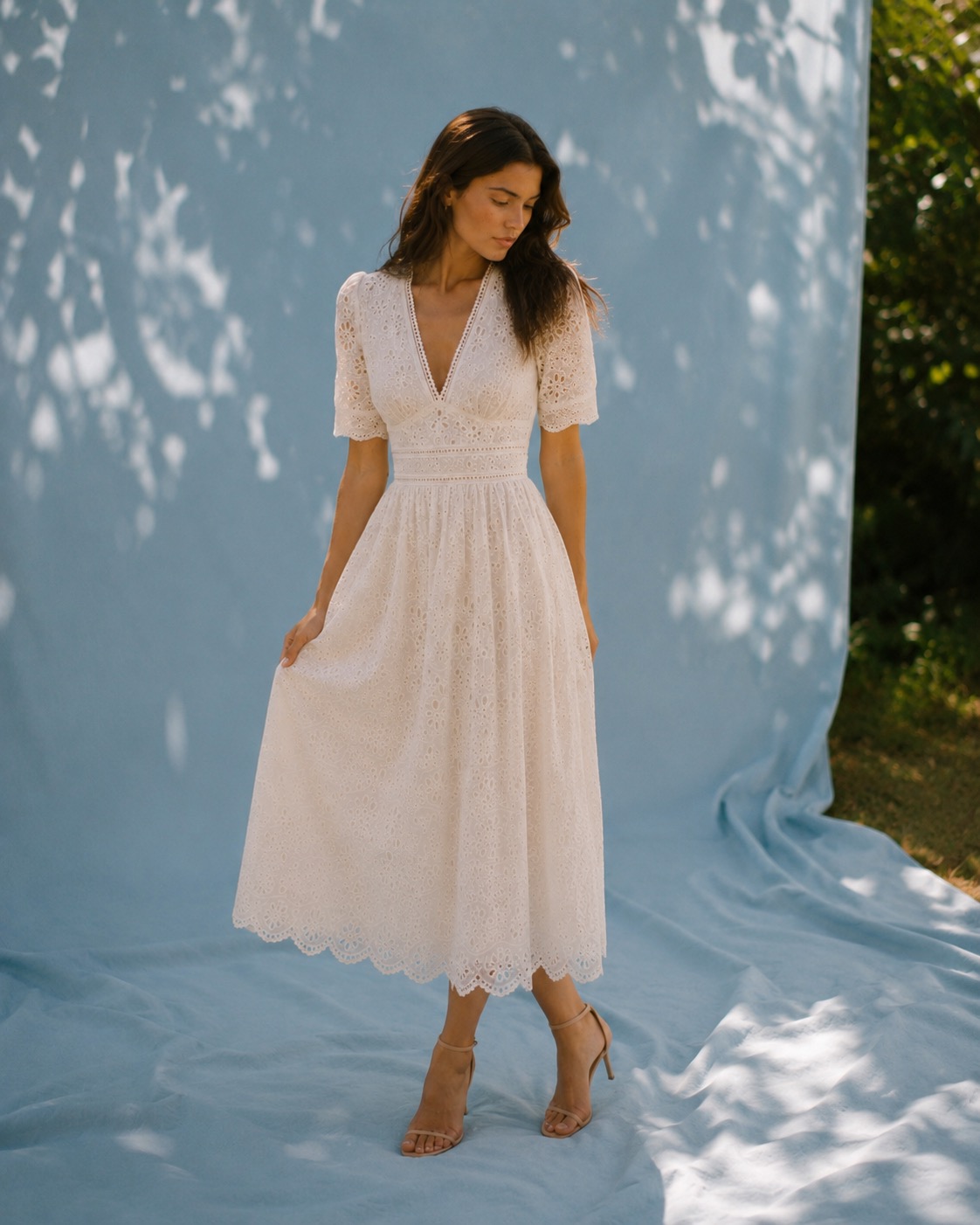 Woman in ivory eyelet dress against a soft blue backdrop