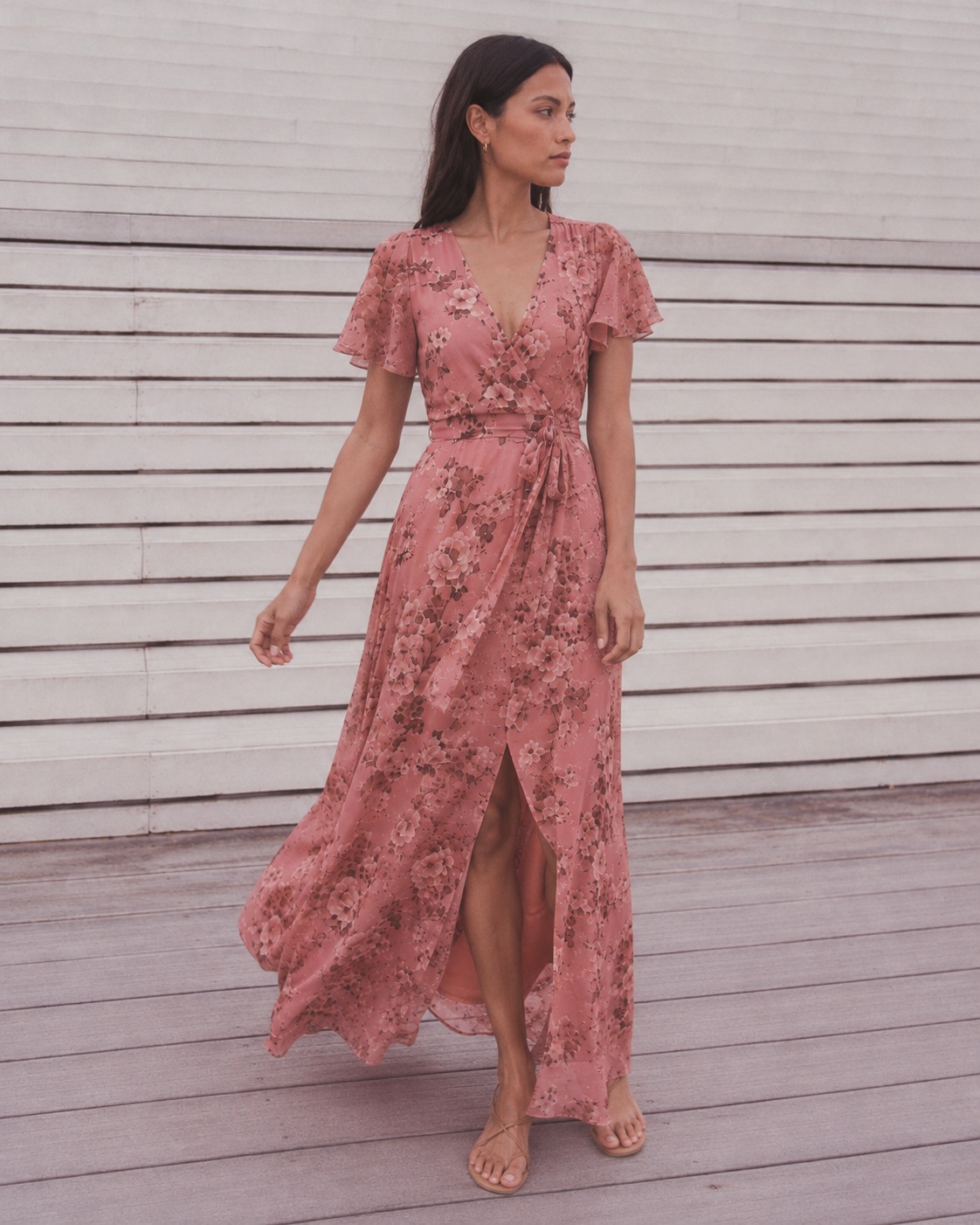 Petite model in an ivory eyelet midi dress crossing a sunlit Paris street — a study in how proportion, not just length, defines petite fit.